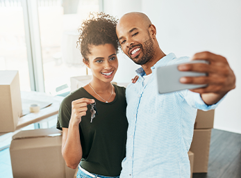 A couple taking a selfie with house keys on moving day